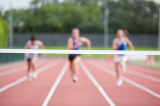 Female athletes running towards finish line on track field