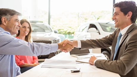 Smiling couple buying a new car at new car showroom